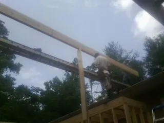 Carpenter setting a ridge beam over a new addition frame — Ice Dam Removal by Roofing Brothers in Saunderstown