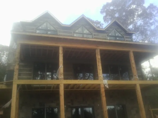 Dormers and porch framing on a large log home under construction — Roof Coating work by our crew in Saunderstown