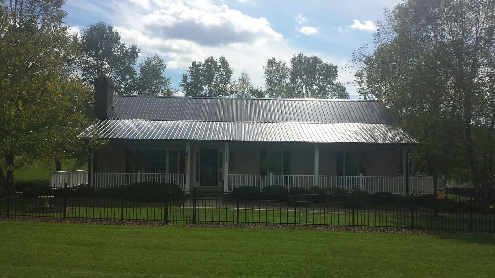 Gray metal roof on a brick ranch with a full width front porch — Gutter Guard Installation work by our crew in Saunderstown