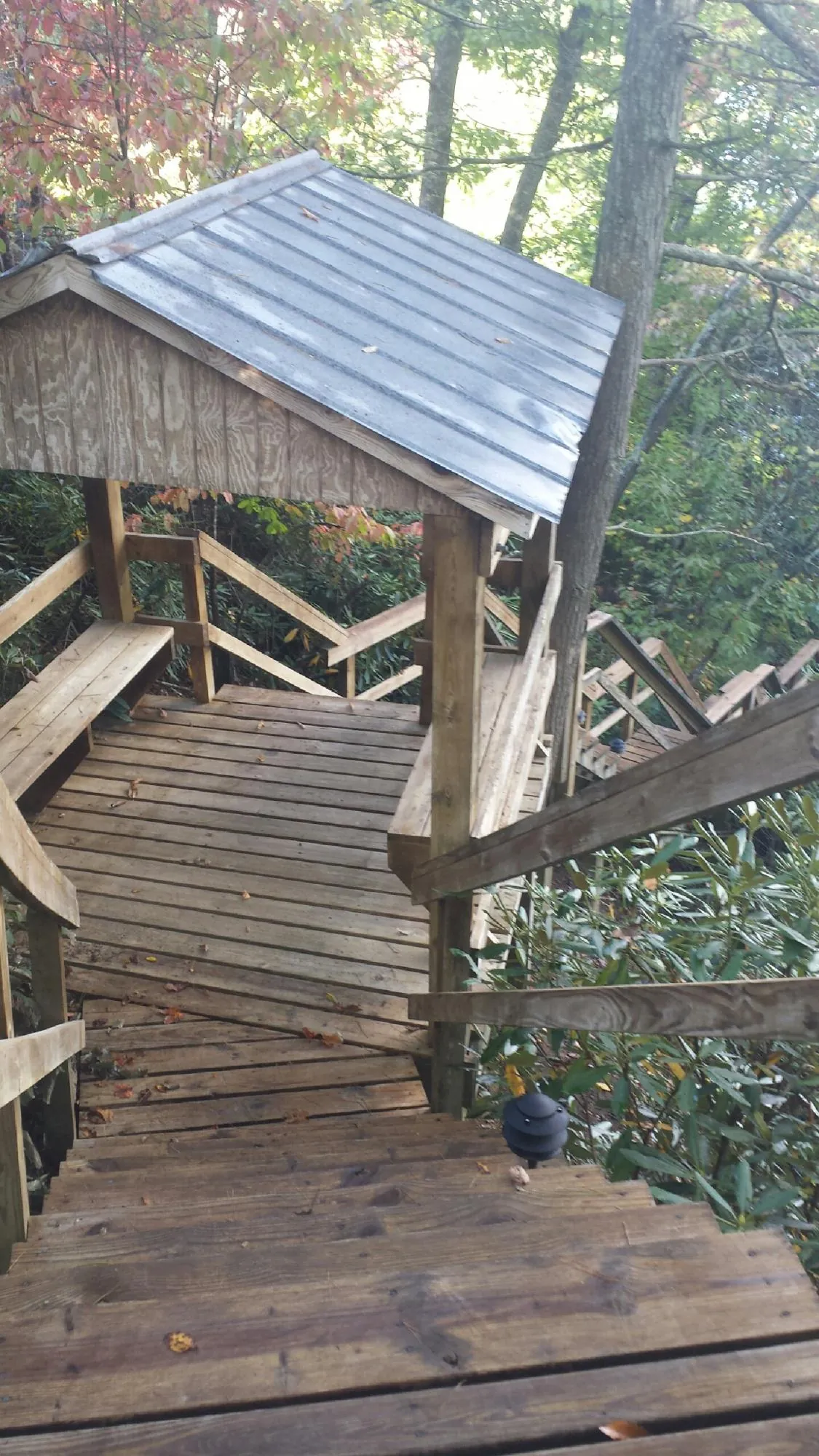 Metal roofed shelter over wooden steps on a wooded walkway — Skylight Repair & Installation work by our crew in Saunderstown