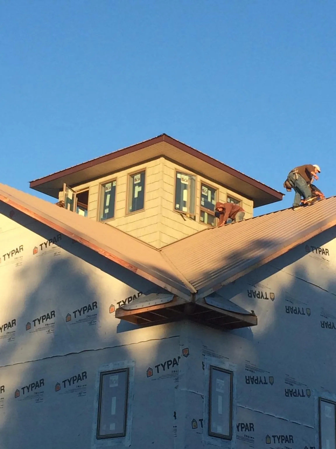 Roofers working around a rooftop cupola on a new metal roof at sunset — Roof Waterproofing in Saunderstown by Roofing Brothers